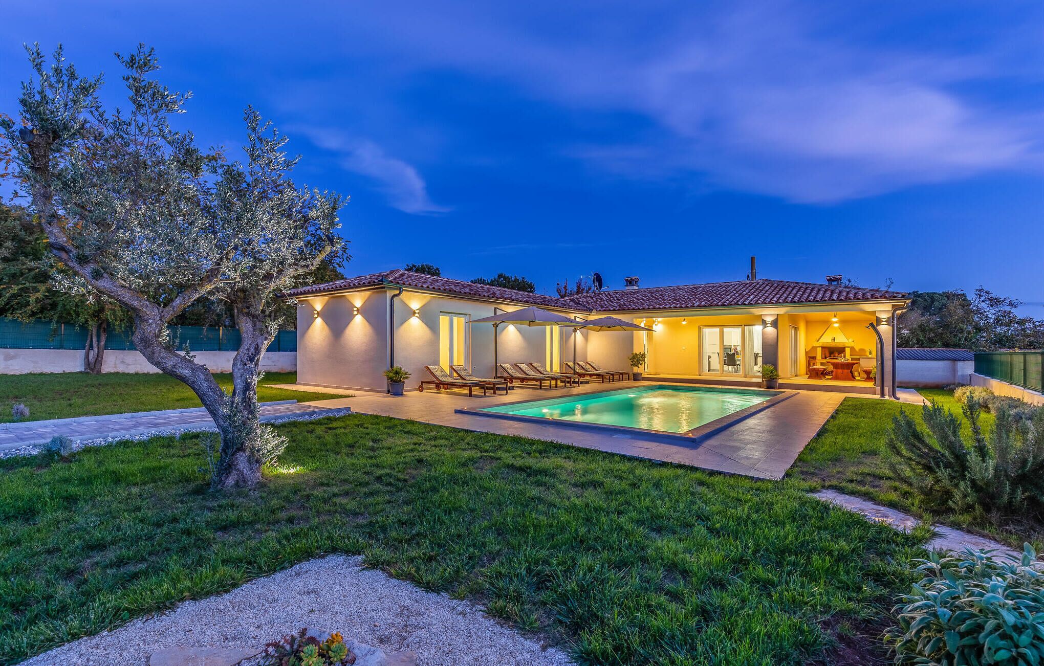 A modern house with a swimming pool, outdoor seating, and a well-maintained garden.