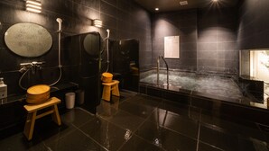 A modern bathroom with a large bathtub, a round mirror, and a wooden stool. - Super Hotel Echizen Takefu (Echizen)