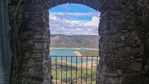 Ein steinerner Bogen führt zu einem Blick auf einen See, der von Hügeln umgeben ist.