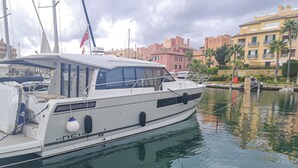Eine weiße Yacht liegt in einer Marina vor einer Stadtkulisse.