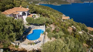 A villa with a swimming pool surrounded by trees, overlooking a coastal area with a clear view of the sea. - Gorgeous home in Lefkada with private swimming pool, can be inside or outside (Lefkada)
