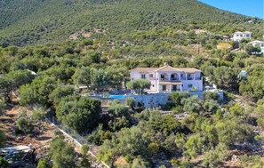 A two-story house with a pool, surrounded by dense vegetation and a mountainous backdrop. - Gorgeous home in Lefkada with private swimming pool, can be inside or outside (Lefkada)