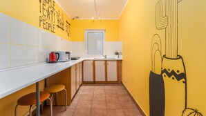 A kitchen with a white countertop, yellow walls, and a mural of a cactus. - Luxhostel24 Warsaw (Warsaw)