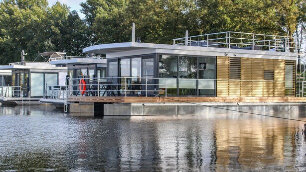 A modern floating house with a glass facade, wooden deck, and a metal railing. - Awesome ship in Well with house sea view (Well)