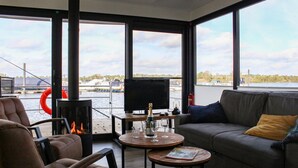 A modern living room with a fireplace, a sofa, and a television. - Awesome ship in Well with house sea view (Well)