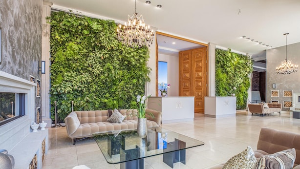 A modern living room with a glass coffee table, beige sofas, and a green vertical garden wall. - Prora Solitaire Avida Loft 7 (Binz)