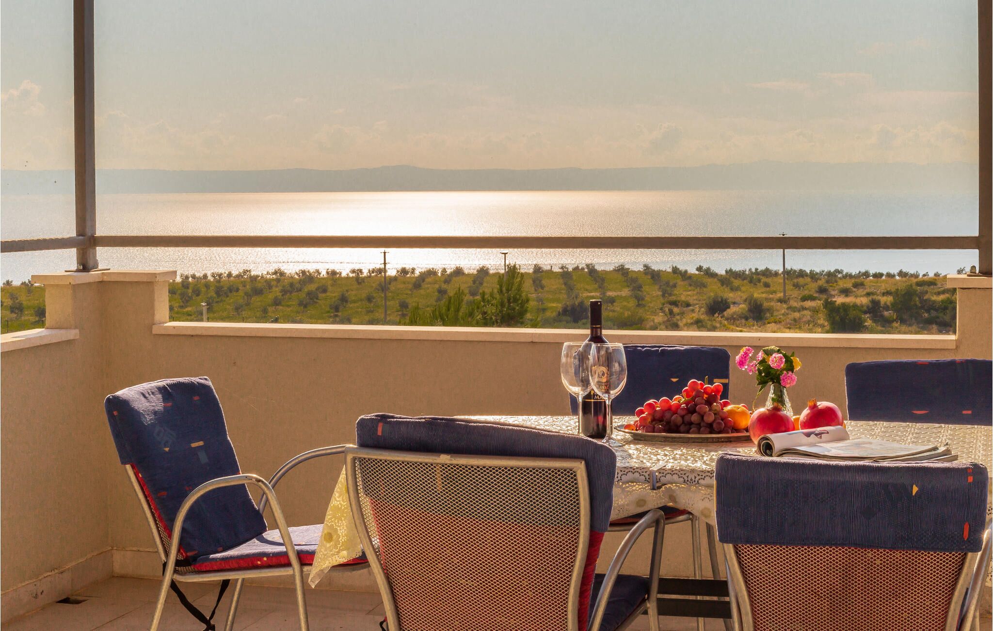 A terrace with a table set for two, overlooking a body of water and greenery.