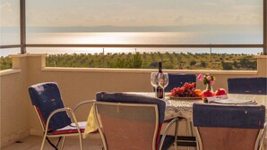 Eine Terrasse mit Tisch für zwei Personen, mit Blick auf ein Gewässer und Grünflächen.