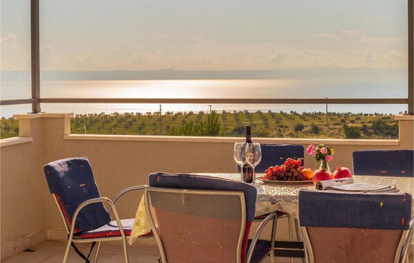 Eine Terrasse mit Tisch für zwei Personen, mit Blick auf ein Gewässer und Grünflächen.