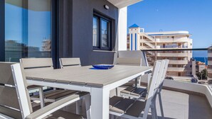 A balcony with a table and chairs, overlooking a building with blue and white balconies.