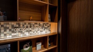 Uma estante de madeira com um compartimento revestido de azulejos exibindo o texto "COCO SHUKU BOOKS".