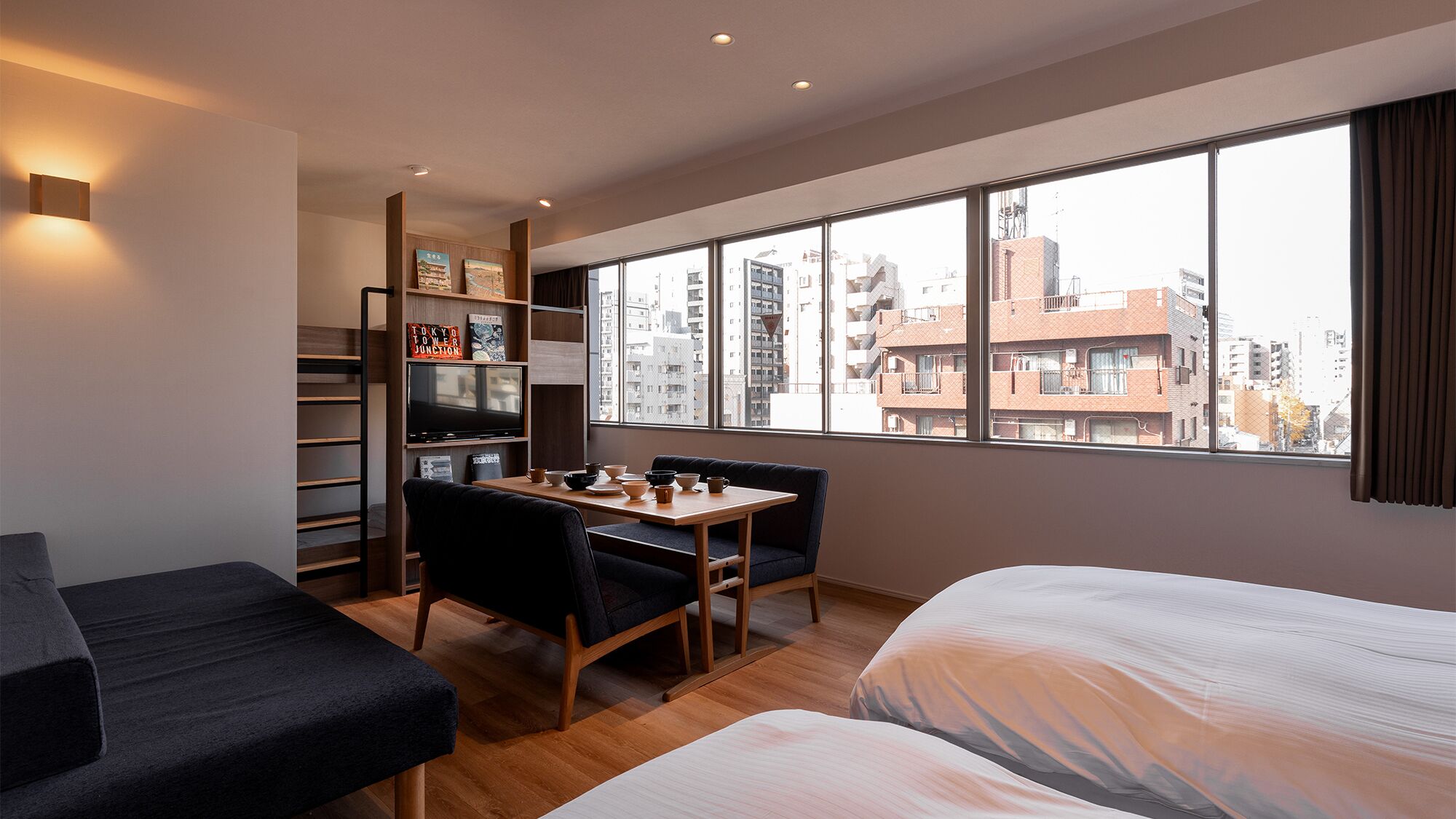 Ett modernt hotellrum med ett stort fönster, en matplats, en soffa och en TV.