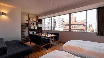 Ett modernt hotellrum med ett stort fönster, en matplats, en soffa och en TV.