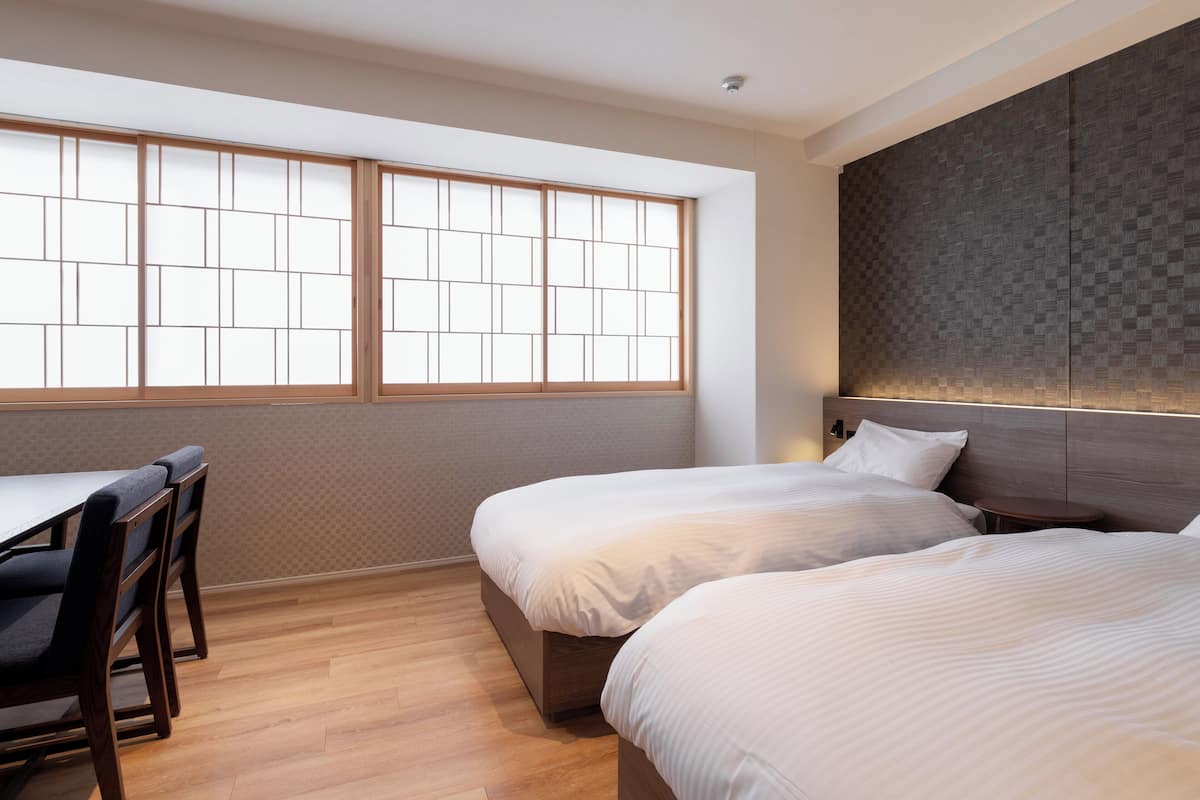 Ein modernes Hotelzimmer mit zwei Betten, einem Schreibtisch und einem großen Fenster mit Blick.