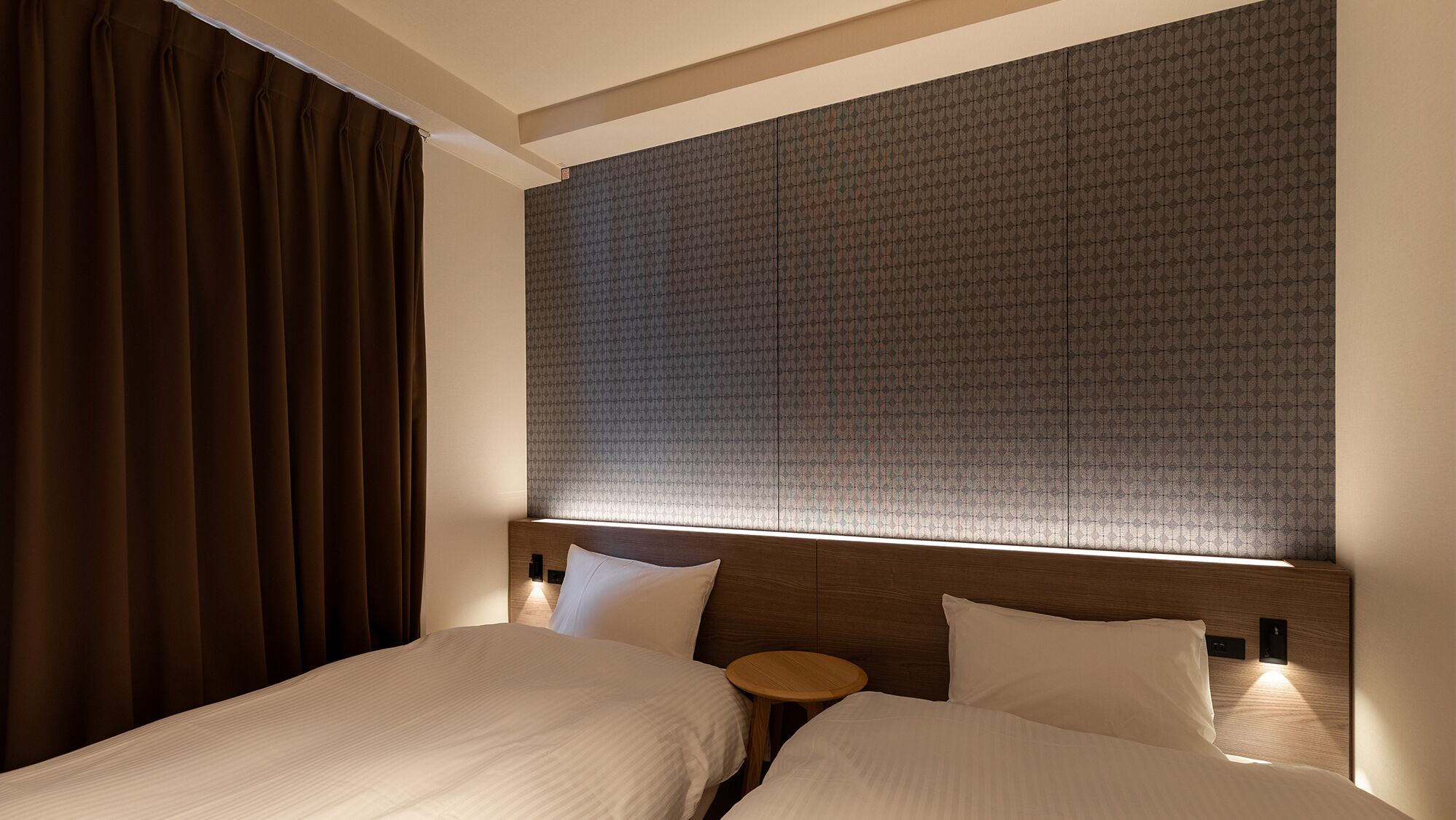 A hotel room with two beds, a wooden headboard, and a patterned wall.