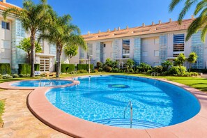 Una piscina amb disseny corbat, envoltada d'un passeig pavimentat.
