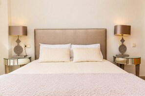 Habitació d'hotel amb un llit gran, dues taules de nit i làmpades.