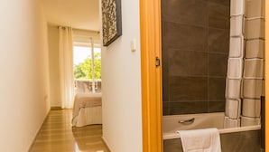 Une salle de bain avec une baignoire, une serviette accrochée au mur et un espace douche.