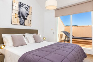 A bedroom with a large bed, a headboard, a painting on the wall, a nightstand, and a window with a view of the outside. - Golden Gardens Duplex Apartment Javea Arenal s, 3 Terraces, AACC, Wifi and only 600m from the Beach (Javea / Xàbia)