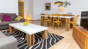 Un salon moderne avec une table basse blanche, un canapé gris, une table à manger en bois et des chaises jaunes.