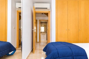 A hotel room with a bed, a wardrobe, and an air conditioning unit.