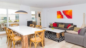 Un salon moderne avec un coin repas, un canapé gris et une grande fenêtre.