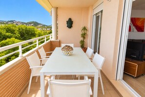 A balcony with a white table and chairs, a decorative bowl, a potted plant, and a Buddha statue.