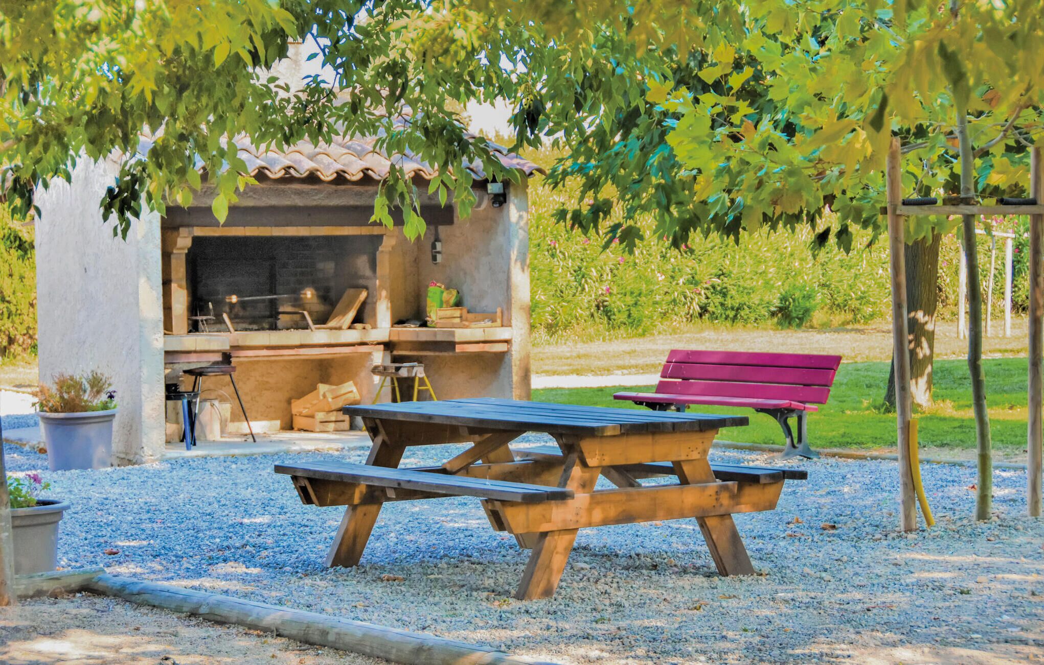 A rustic outdoor seating area with a wooden table and benches, a barbecue grill, and a small shed.