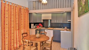 A modern kitchen with grey cabinets, a dining table with chairs, and a vase with flowers.