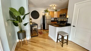 A compact kitchen with wooden flooring, a refrigerator, a microwave, and a sink. - The Tropical Bungalow (Safety Harbor)
