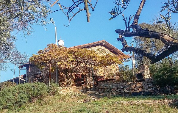 A stone building with a sloped roof, surrounded by greenery and trees. - 2 bedroom cozy home in Roquebrun (Roquebrun)