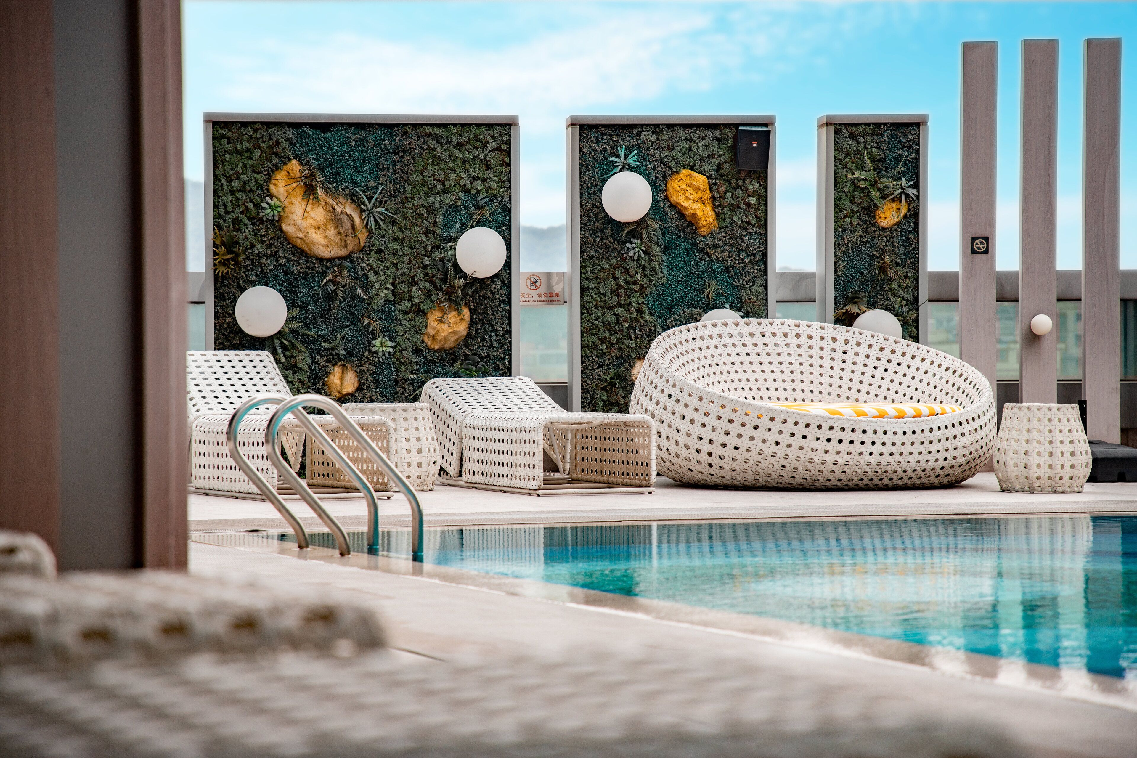 A poolside area with lounge chairs and a decorative wall.