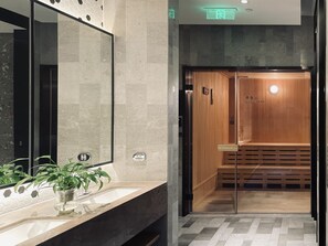 A modern bathroom with a large mirror, a sink, and a potted plant.