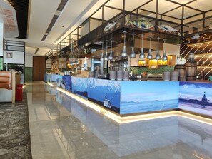 A hotel lobby with a reception desk, a staircase, and a view of the sea.