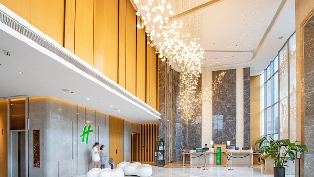 Um lobby moderno com balcão de recepção, área de estar e um grande lustre.