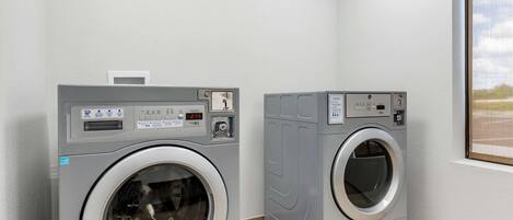 Two front-loading washing machines in a laundry room with a window.