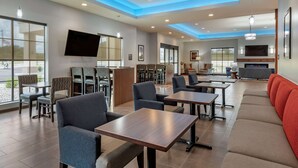 A modern hotel lobby with seating areas, tables, and a flat-screen TV mounted on the wall. - Comfort Suites Dry Ridge (Dry Ridge)