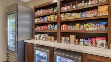 A self-service snack and beverage area with refrigerated sections and shelves stocked with various snacks and drinks.