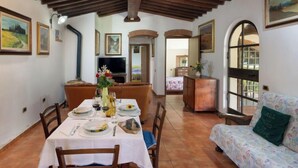 A dining area with a table set for four, a sofa, and a television in the background. - Bouganville by Interhome (Bibbona)