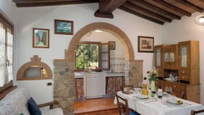 A cozy dining area with a stone fireplace, wooden beams, and a table set for a meal. - Bouganville by Interhome (Bibbona)
