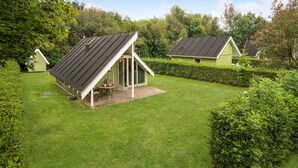 Ein kleines, grünes Einfamilienhaus mit Satteldach und überdachter Terrasse.