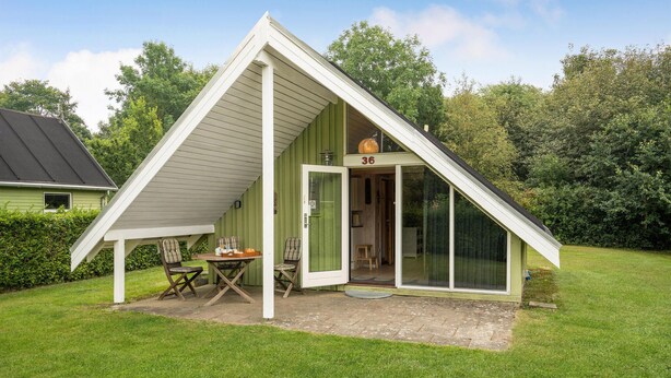 Ein kleines, eingeschossiges Haus mit einem geneigten Dach, einer grünen Tür und der Hausnummer 36.