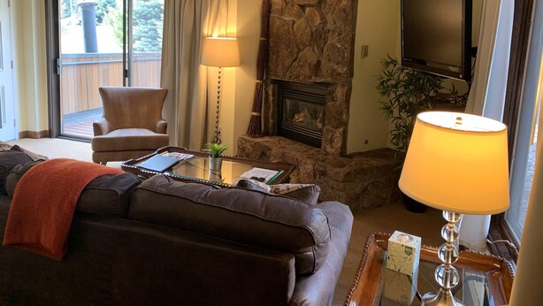 A living room with a stone fireplace, a television, a sofa, and a chair. - Christmas Skiing at Vail, Just minutes away from the slopes and restaurants (Vail)