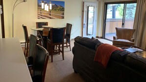 A living room with a sofa, a dining table with chairs, a painting on the wall, and a sliding glass door leading to an outdoor area. - Christmas Skiing at Vail, Just minutes away from the slopes and restaurants (Vail)