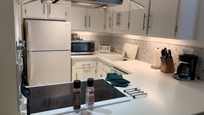 A modern kitchen with white cabinets, a stainless steel refrigerator, a microwave, a toaster, and a coffee maker. - Christmas Skiing at Vail, Just minutes away from the slopes and restaurants (Vail)