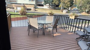 A wooden deck with a table and chairs, overlooking a street with a building labeled "Snow Farm". - Christmas Skiing at Vail, Just minutes away from the slopes and restaurants (Vail)