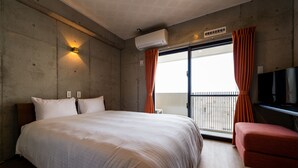 Hotelkamer met een groot bed, een rode stoel, een airconditioning en uitzicht op het balkon.