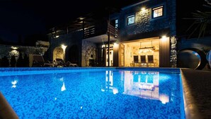A swimming pool with a stone facade and a bar area with seating. - Beautiful home in Tribalj (Tribalj)