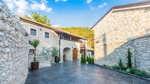 A courtyard with stone walls, a tiled floor, and a building with a balcony. - Beautiful home in Tribalj (Tribalj)