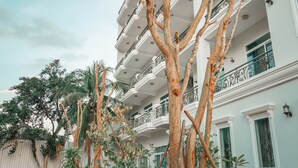 A multi-story building with balconies and a tree in the foreground. - Intanou Boutique Hotel Kampot (Kampot)